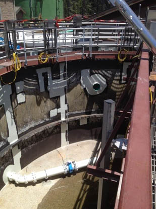 A large industrial tank or silo with pipes and safety railings, possibly used for water treatment or storage.