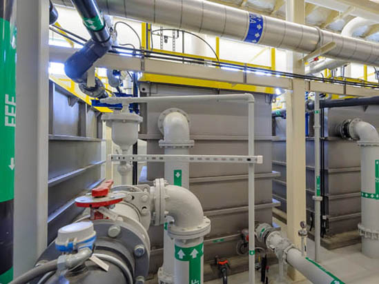 Industrial pipes and machinery in a facility, featuring valves, ducts, and structural elements.