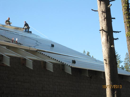 Construction workers installing a metal roof on a building.