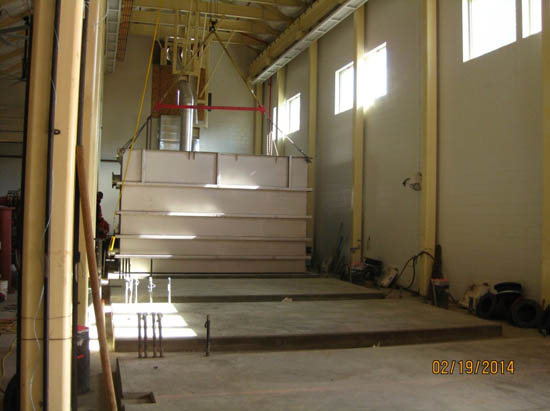Industrial warehouse interior with large equipment suspended, pipes and cables visible, taken on 02/19/2014.