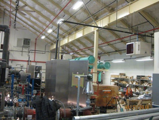 Industrial workshop with machinery, pipes, shelves, and tools. Ceiling with insulation and lights.