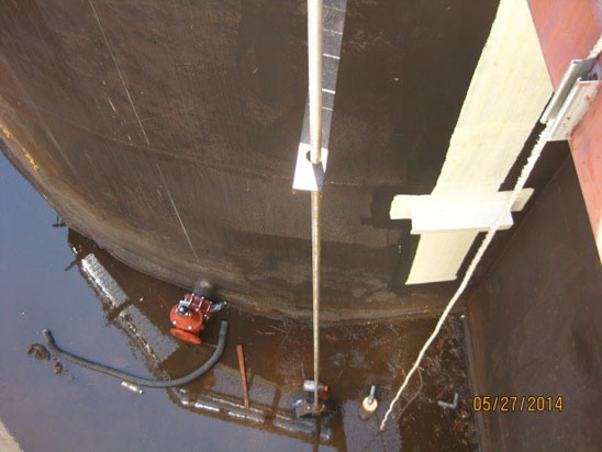 Industrial tank interior with equipment and wet floor.