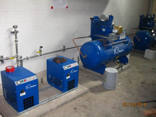 Blue industrial air compressors and other machinery in a workshop.