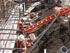 Construction workers at a site with rebar, safety gear, and equipment.