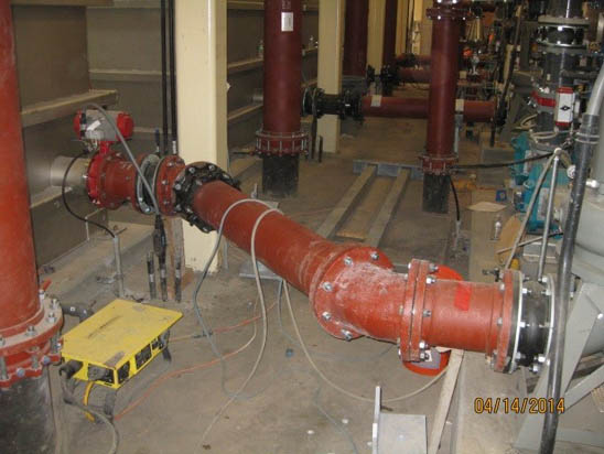 A red industrial pipe system with valves and wiring in a mechanical room.