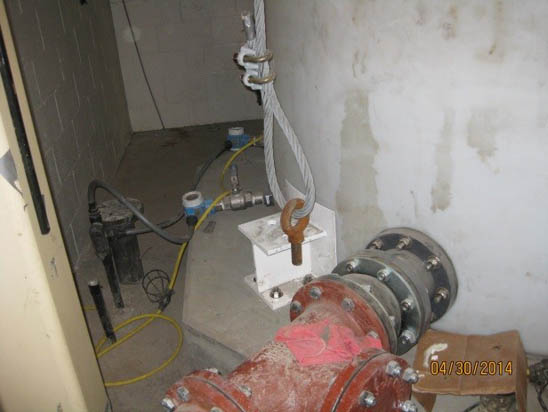 A mechanical setup with pipes, a metal cable, and equipment in a utility room.