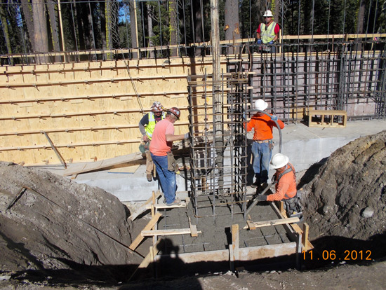 Construction workers building a reinforced concrete structure with rebar and wooden forms.