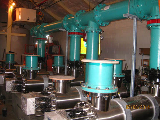 Industrial pipes and valves in a mechanical room.