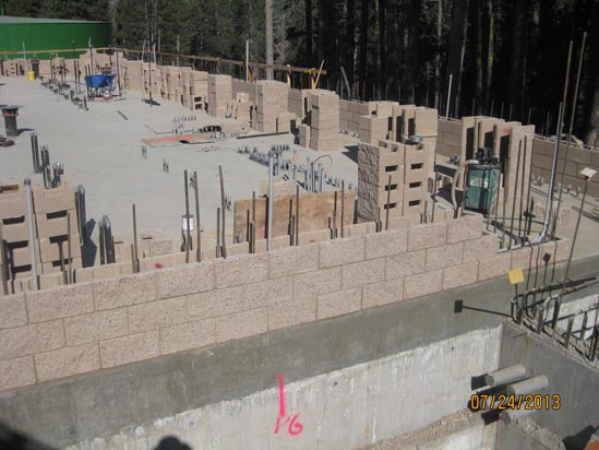 Construction site with partially built brick walls and rebar sticking out. It appears to be a foundation or basement area.