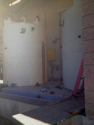 Two large industrial tanks, a ladder, and some piping in a facility.