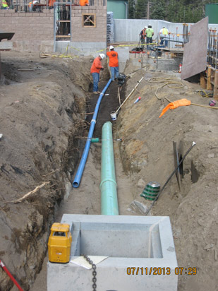 Workers laying pipes in a trench at a construction site.