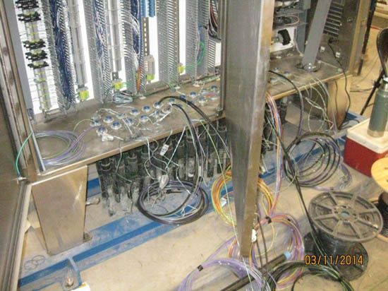 Electrical panels with various cables and wiring connected, placed on a floor.