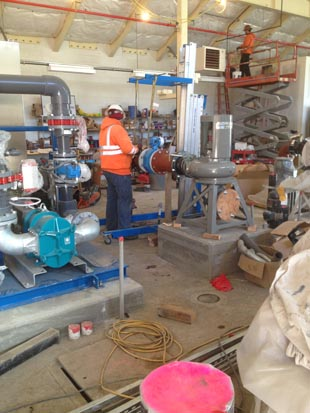 Workers in a workshop setting, handling industrial equipment with various tools and machinery around.