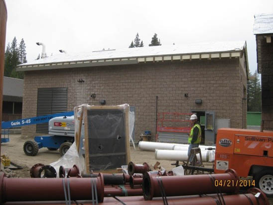 Construction site with a worker, building, equipment, and materials.