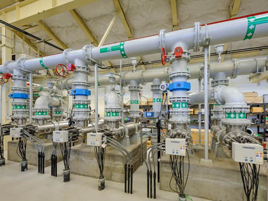 Industrial piping system with valves, gauges, and control panels in a facility.
