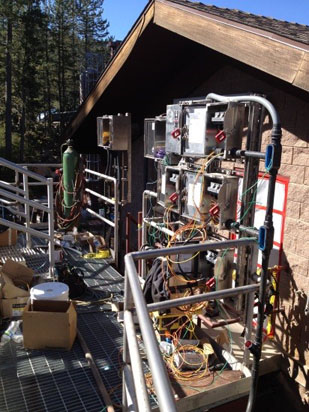 A setup with electronic equipment, wires, and gas cylinders outside a building.