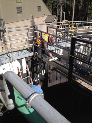 Two workers on elevated platforms handling equipment at an industrial facility.