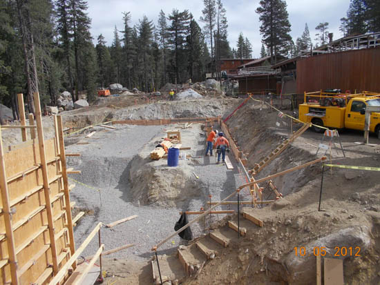 Construction site with workers and machinery in a forested area.