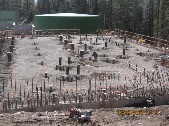 Construction site with a gravel base, rebar, and concrete forms, surrounded by a forest. Date stamp: 05/29/2013.