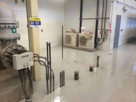 Industrial room with machinery, cables, and warning signs on a polished floor.