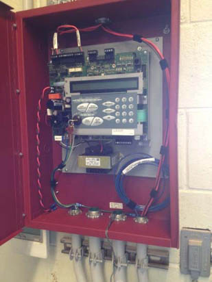 A red electrical panel with wires, circuit board, and control buttons inside.