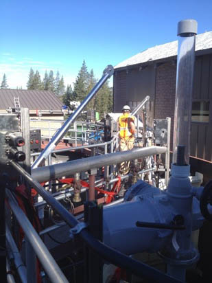 An industrial area with machinery and a person wearing a hard hat and safety vest.