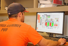 Person in orange shirt and cap looking at a computer screen with a graphical interface.
