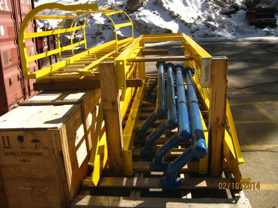 Wooden crates and yellow metal frames with blue pipes, outdoors.