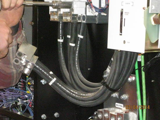 Cables connected to an electrical panel, with a hand using a tool.