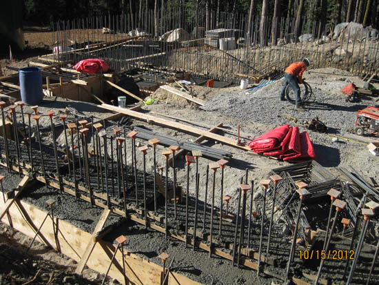 Construction site with rebar, concrete forms, and a worker handling equipment.