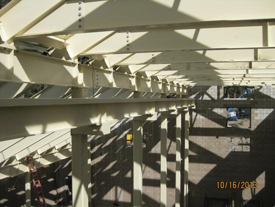 Steel beams and framework of a building under construction, with sunlight casting shadows.