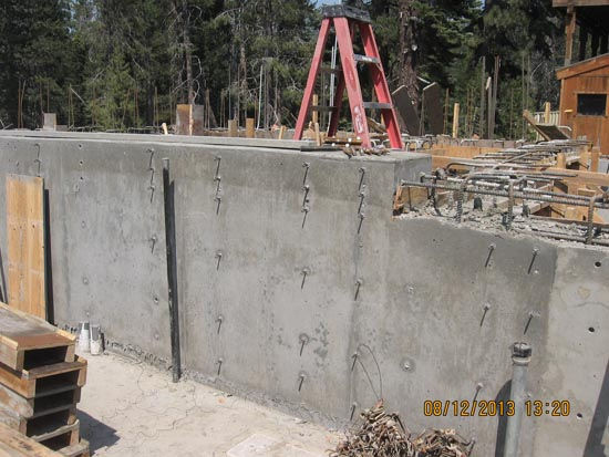 Construction site with concrete wall, ladder, and rebar framework.