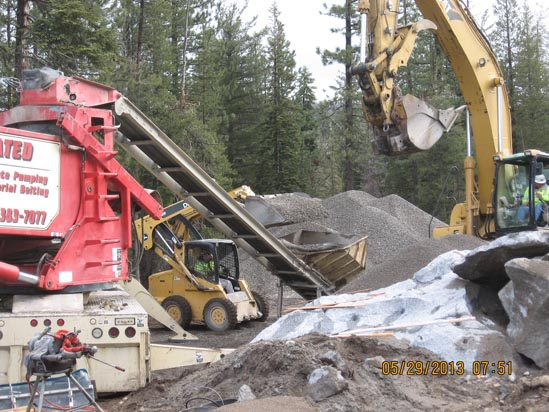 Construction site with excavators, a loader, and a conveyor belt moving gravel.
