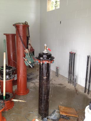 A plumbing setup with pipes, valves, and tools in a utility room.
