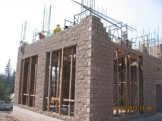 Building under construction with workers on site, framework, and rebar visible. Date on photo: 08/12/2013.