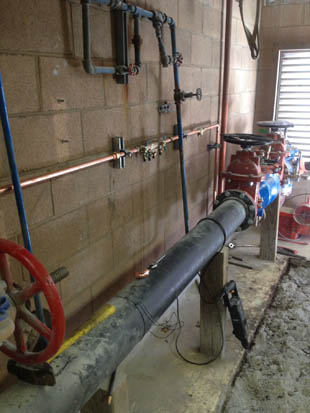 Industrial piping system with valves, gauges, and fittings inside a building.