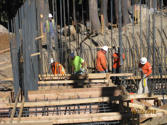 Construction workers building with wooden frames and rebar.