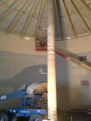 A construction lift inside a large cylindrical structure with a central column.