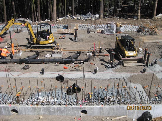 Construction site with machinery, rebar, and workers.