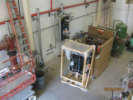 Industrial equipment and machinery in a workshop with ladders, tools, and pipes around.