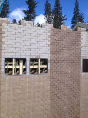 A partially constructed brick building wall with windows and trees in the background.