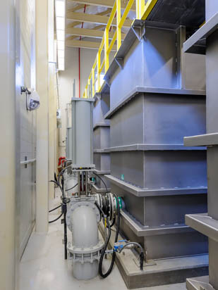 Industrial equipment and large metal tanks with pipes and railings in a facility.