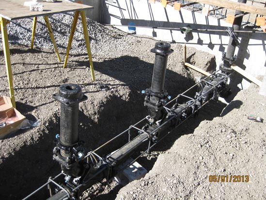 Construction site with pipes installed in trenches, supported by a table and wooden structures.