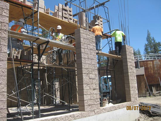 Construction workers building with scaffolding and bricks.