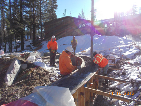 Workers pouring concrete on a snowy construction site.