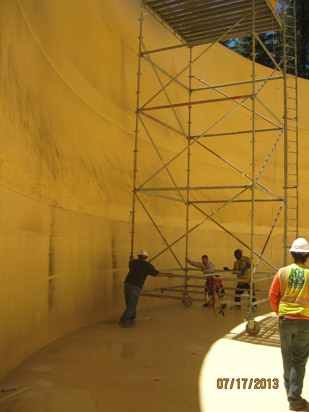 Workers adjusting scaffolding inside a large yellow structure.