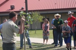 May contain: plant, tree, adult, female, person, woman, male, man, clothing, hat, grass, pants, people, footwear, shoe, nature, outdoors, and t-shirt