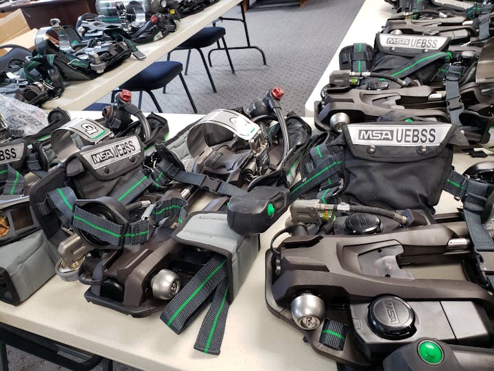 The image shows multiple MSA UEBSS harnesses and equipment arranged on tables, likely for safety or rescue operations.