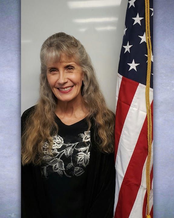 A smiling woman with a U.S. flag.