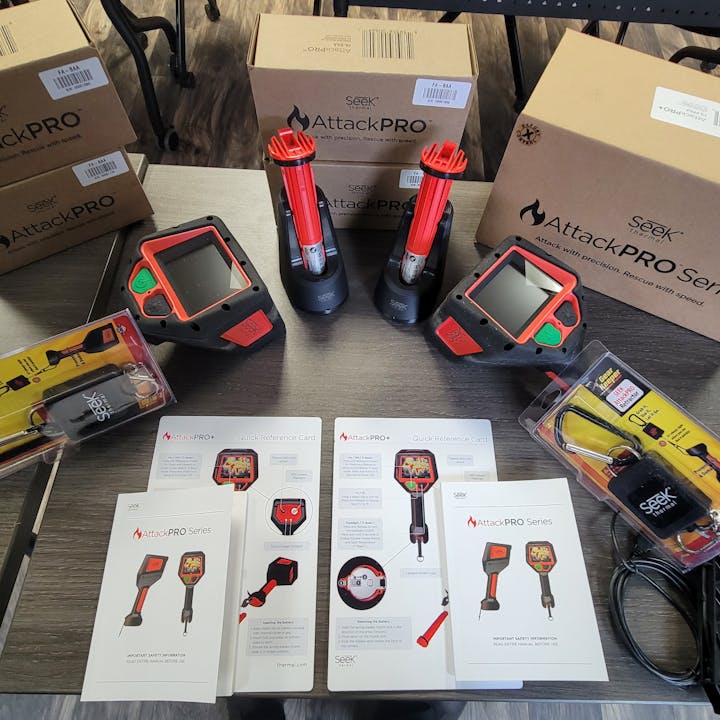 Thermal imaging cameras, accessories, and product manuals on a table.